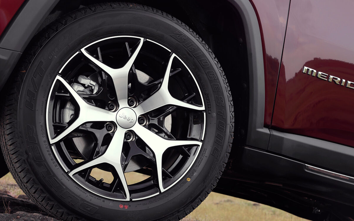 Close-up of the Jeep Meridian alloy wheel and Meridian badge on a red car