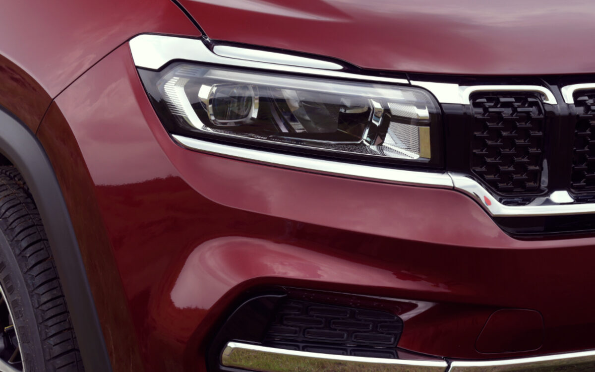 Close-up of the LED headlamp and grille of a red Jeep Meridian