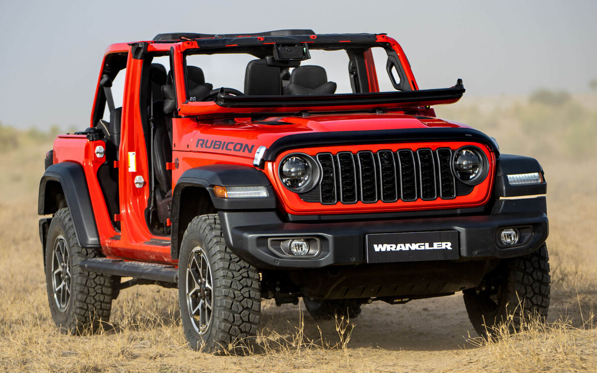 Jeep Wrangler Rubicon in Firecracker Red, front view on dry grassland with the doors and roof removed