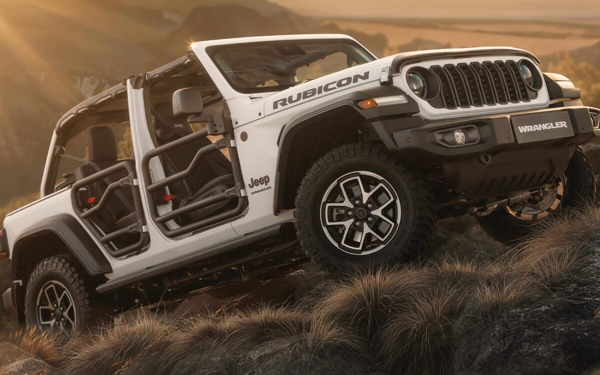 White Jeep Wrangler Rubicon with doors off climbing a rocky slope at sunset