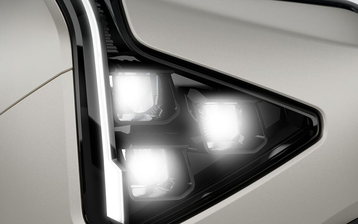 Close-up of the Kia Carens Clavis triangular LED headlamp with its vertical light signature