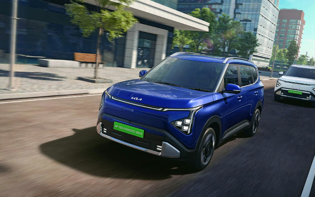 Kia Carens Clavis EV in Imperial Blue driving on a city road with a white EV behind
