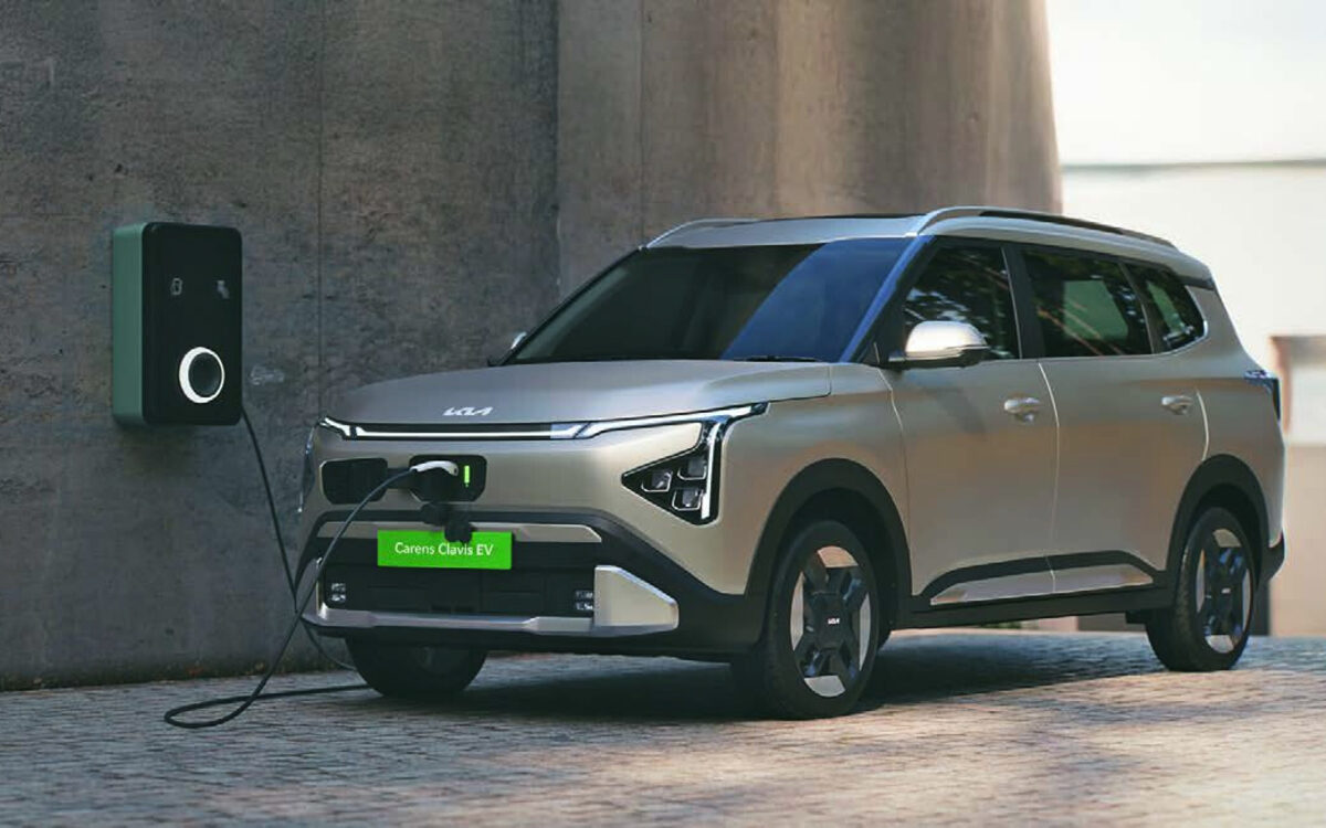 Kia Carens Clavis EV in silver-beige plugged in to a wall-mounted home charger