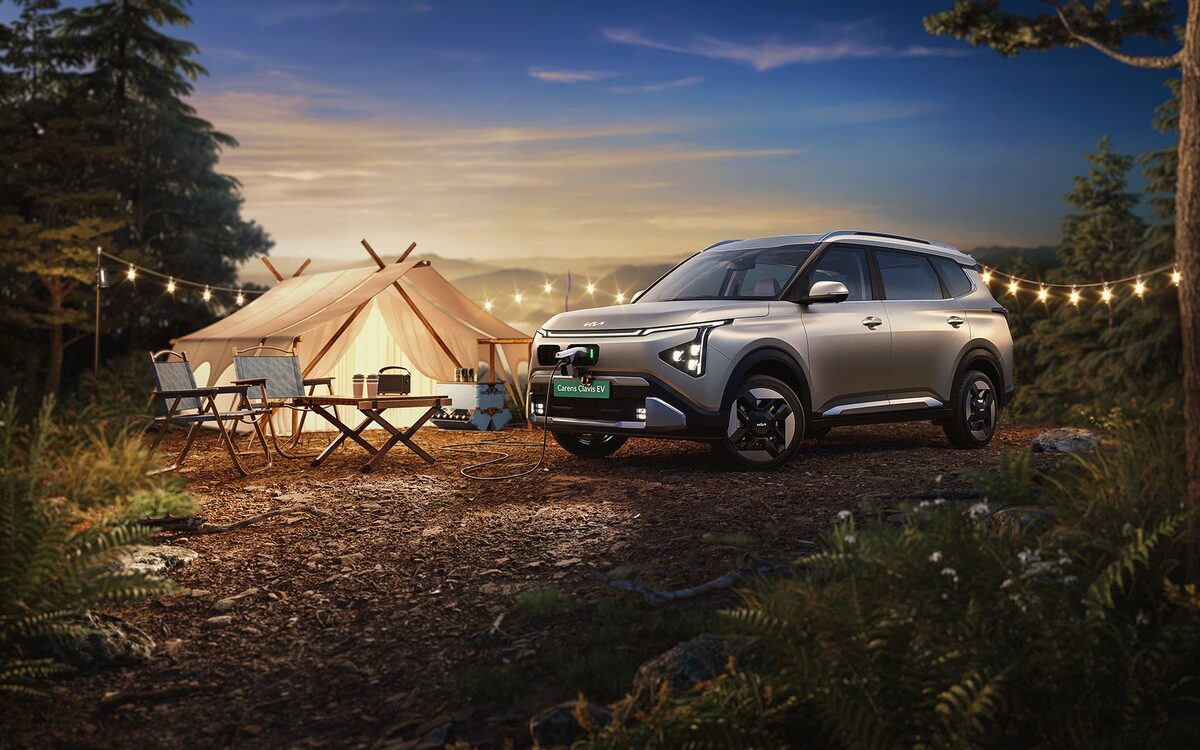 Kia Carens Clavis EV parked at an evening campsite with a tent and string lights
