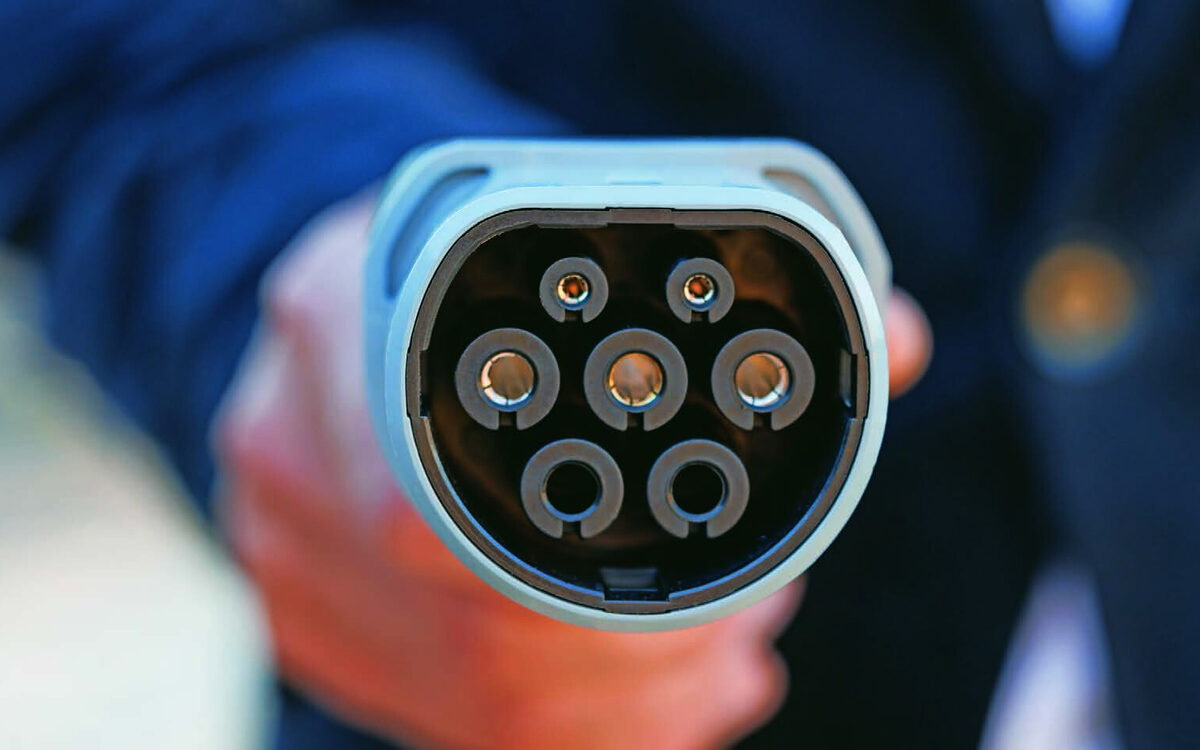 Close view of an EV charging connector plug held in a hand
