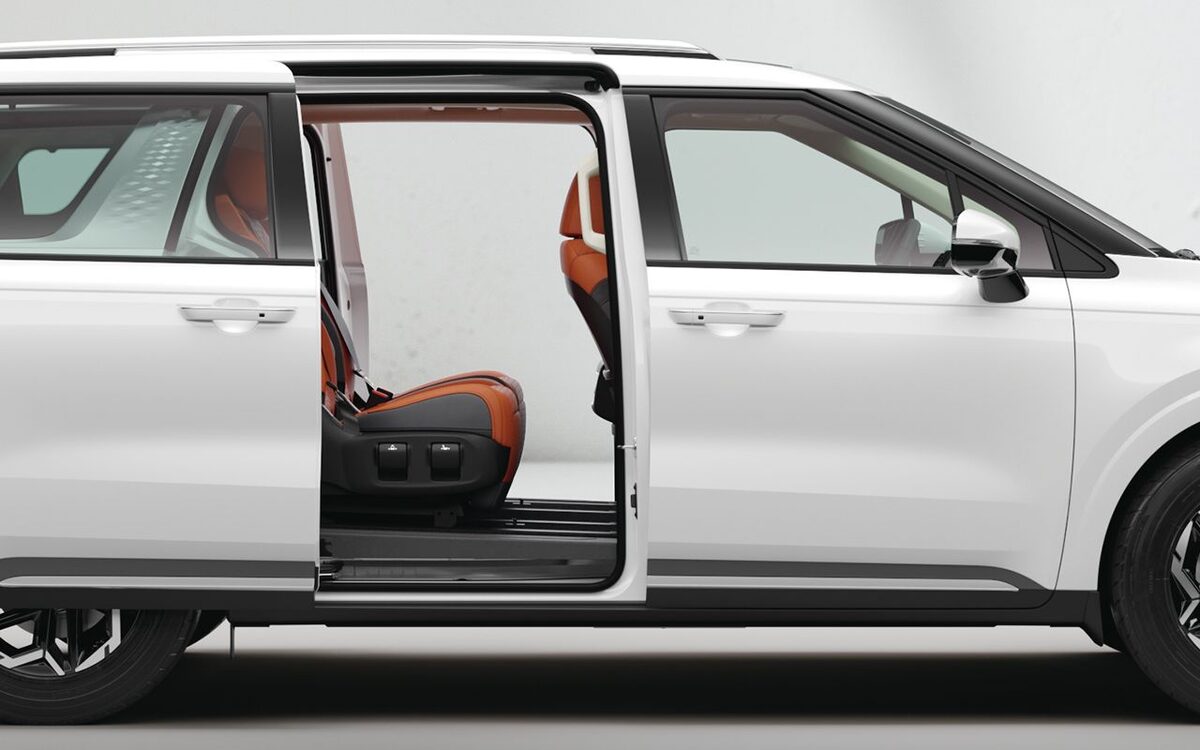 Kia Carnival white side profile with the sliding door open showing the second row seat