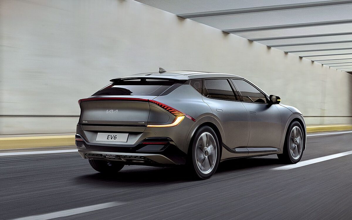 Kia EV6 driving through a tunnel, seen from the rear three-quarter with its light bar glowing