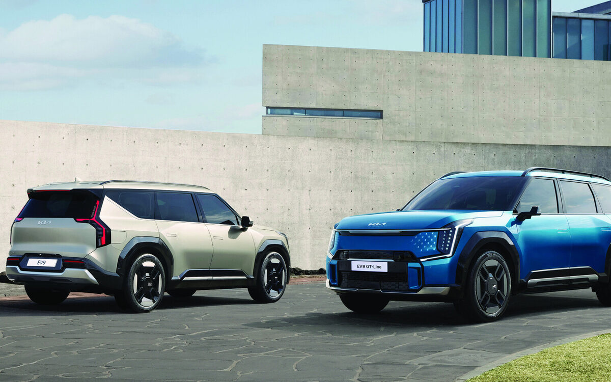 Kia EV9 in light grey and blue parked side by side outside a modern house