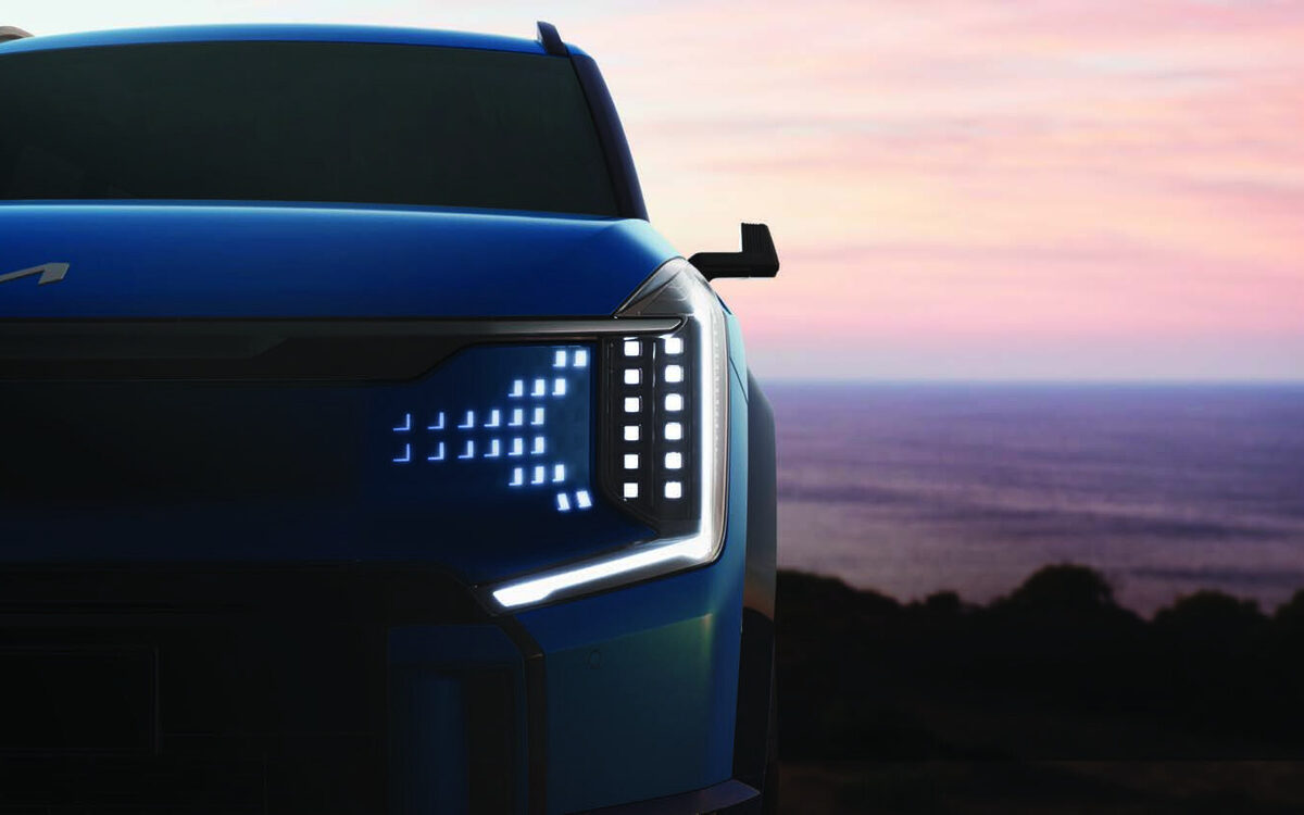 Close-up of the Kia EV9 digital pattern headlamp and daytime light on a blue car