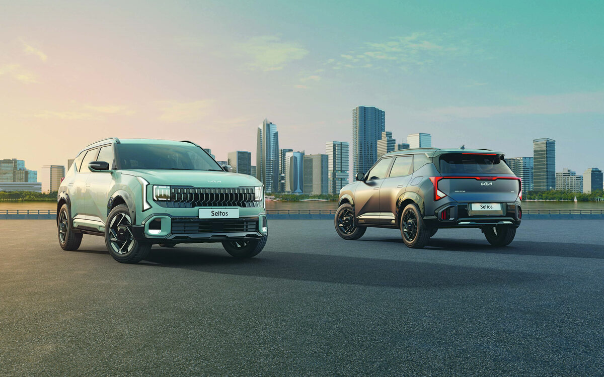Two Kia Seltos SUVs side by side in a city, one showing the front and one the rear with the connected tail lamp