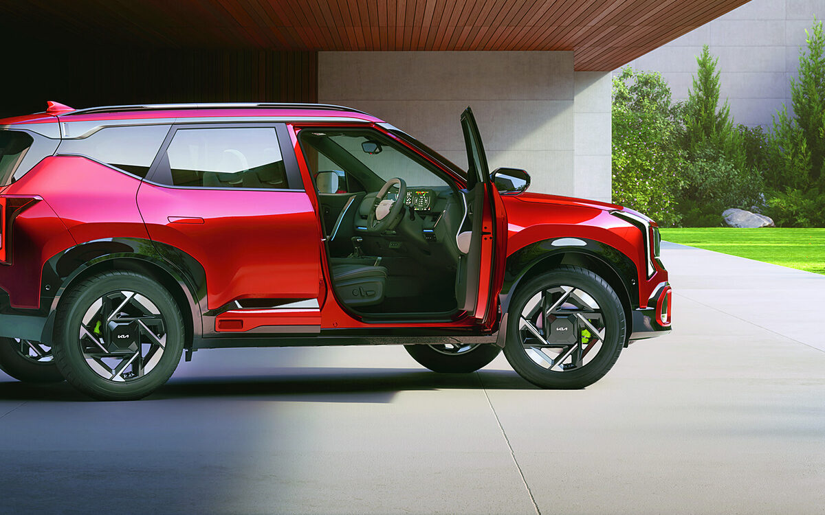 Kia Seltos in red seen from the side with the front door open under a covered porch