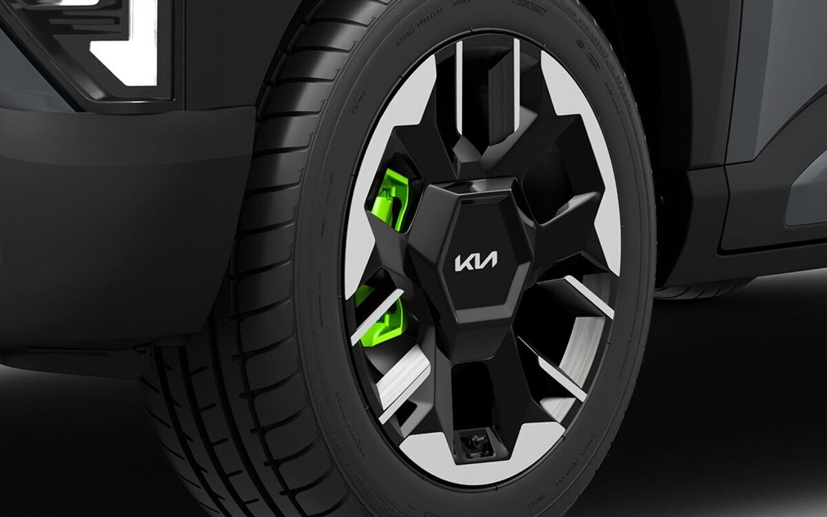 Close-up of the Kia Syros front bumper corner with fog lamp and the black alloy wheel with green brake caliper