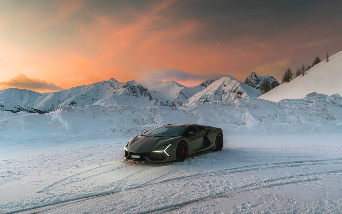 Lamborghini Revuelto in dark green driving on a snowy mountain plain at sunset