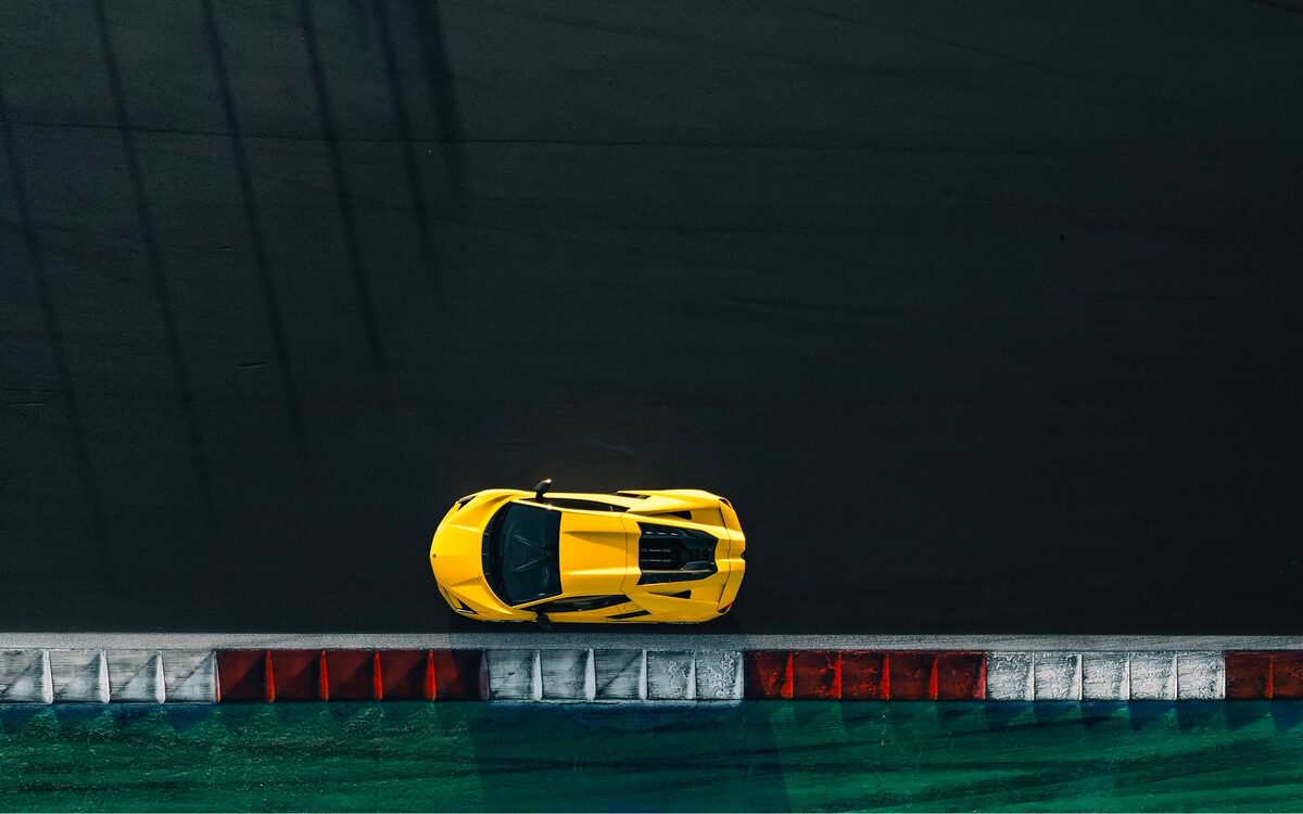 Lamborghini Revuelto in yellow, seen from directly above beside a race-track kerb