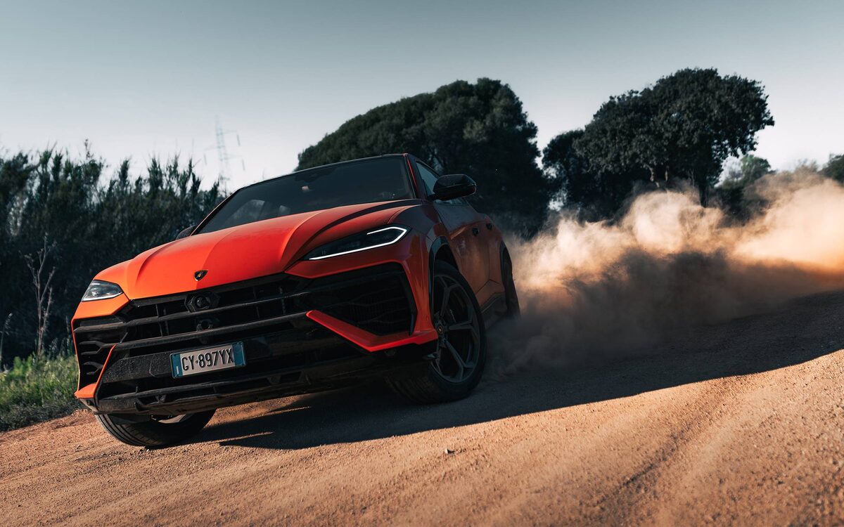 Lamborghini Urus SE in orange throwing up dust on a dirt road
