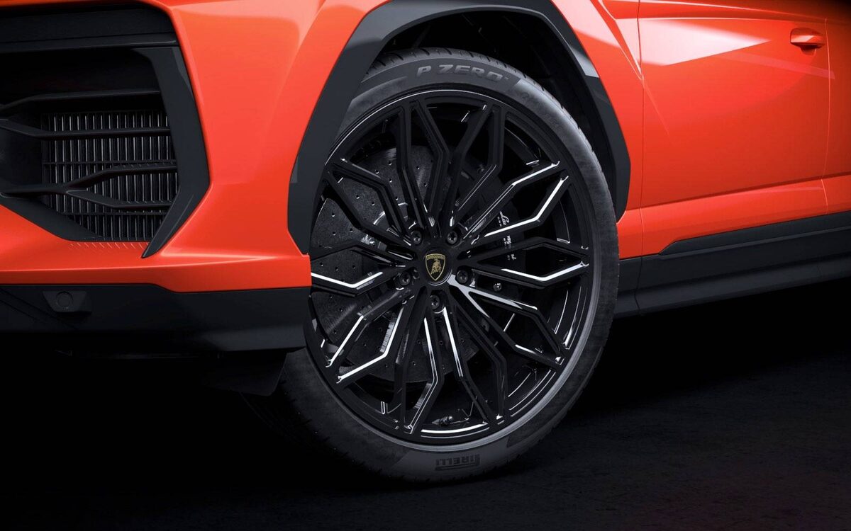 Lamborghini Urus SE close-up of a black multi-spoke alloy wheel and front fender in orange