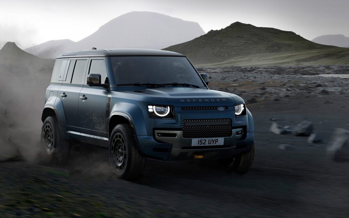 Land Rover Defender in dark blue driving towards the camera on a muddy mountain trail