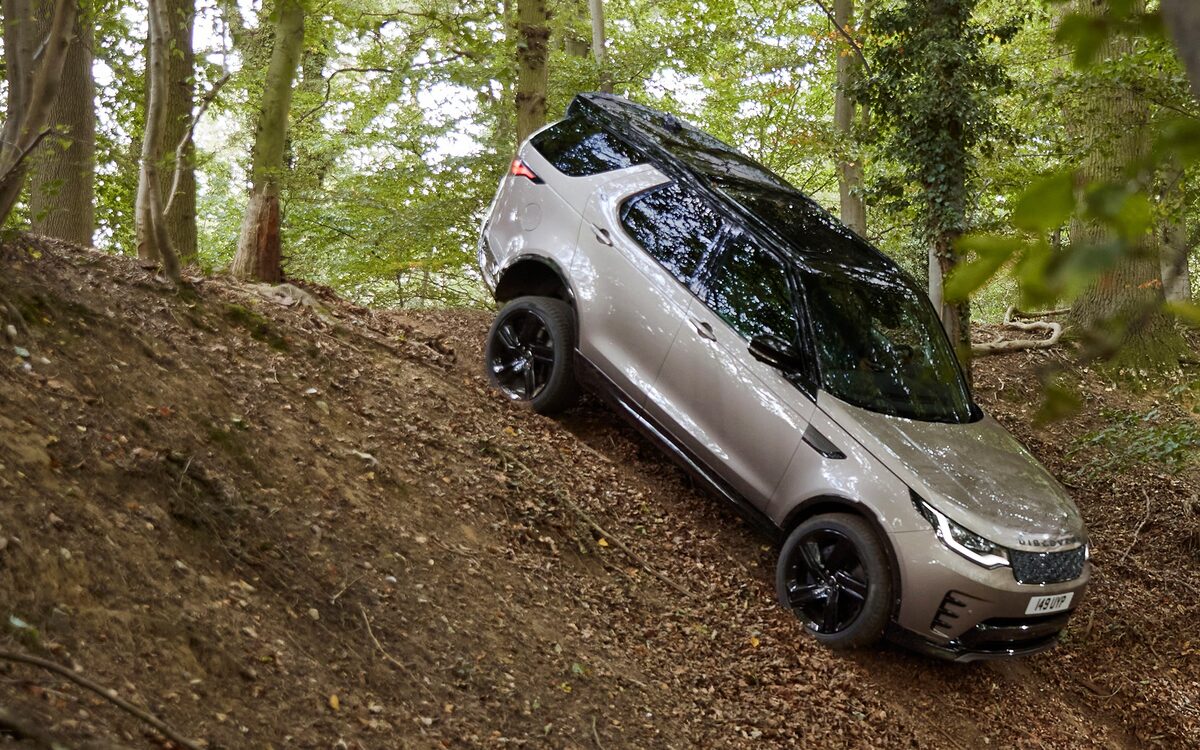 Land Rover Discovery in silver driving down a steep forest slope
