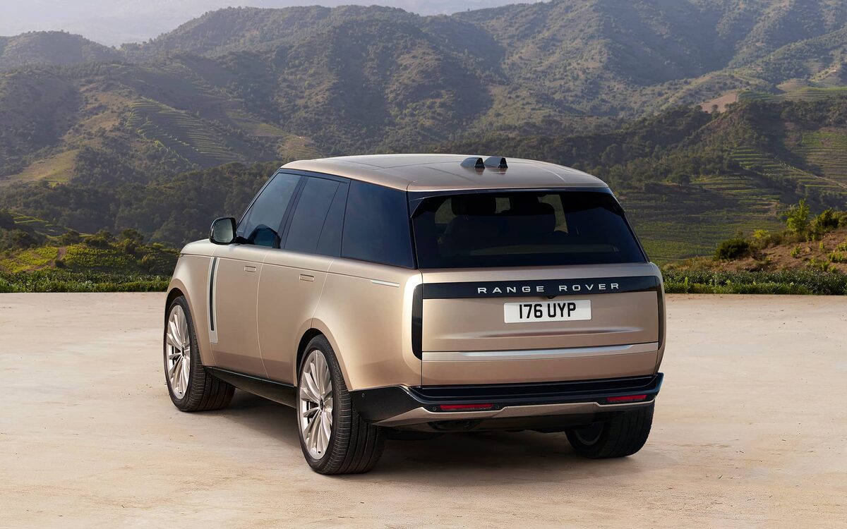 Range Rover in gold with a dark roof on a hillside, rear three-quarter view