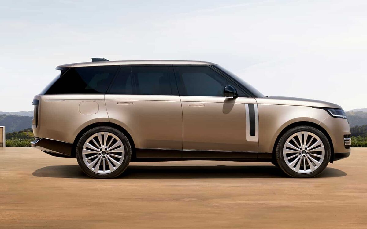 Range Rover in gold on dry ground with hills behind, full side profile
