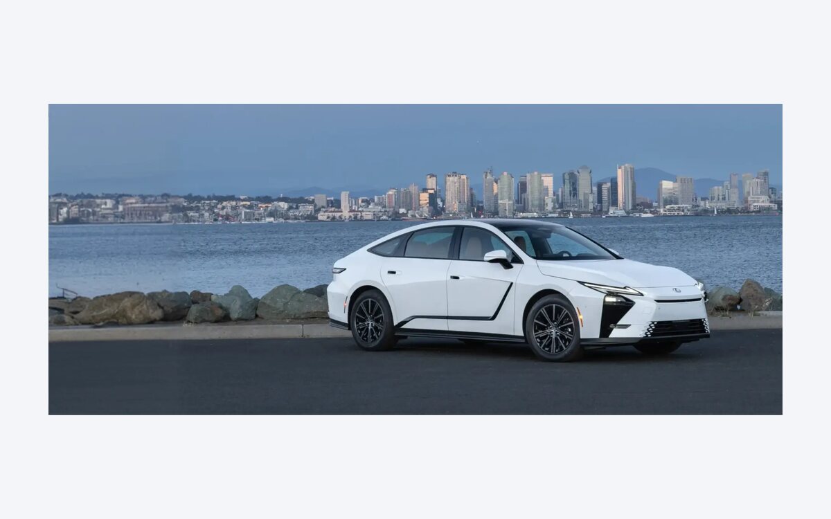 Lexus ES 350h in white parked on a waterfront road with a city skyline behind