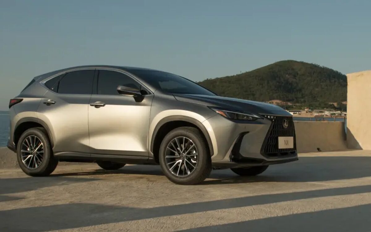 Lexus NX parked on a seaside road with a hill in the background, front three-quarter view