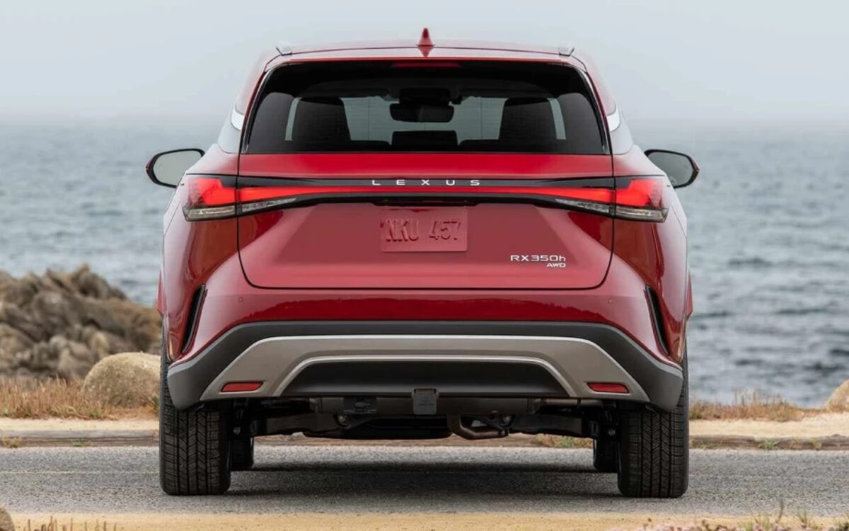 Red Lexus RX 350h seen from behind with the full-width tail lamp, ocean in the background