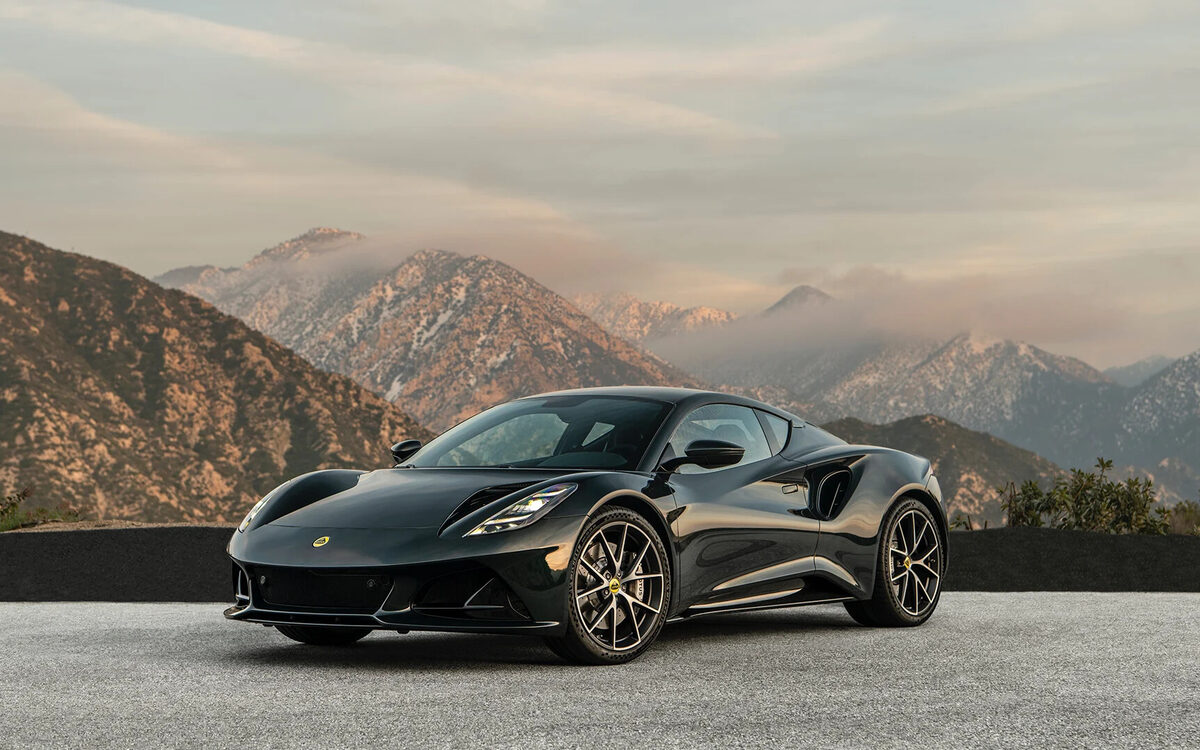 Lotus Emira in dark green, front three-quarter view on a mountain road
