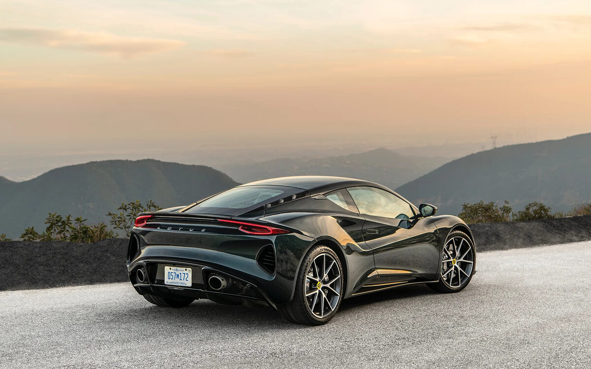 Lotus Emira in dark green, rear three-quarter view at sunset