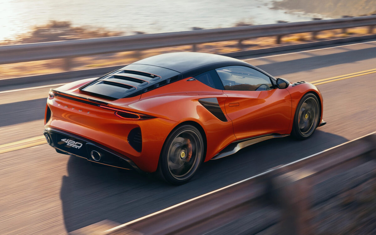 Lotus Emira in orange driving along a coastal road