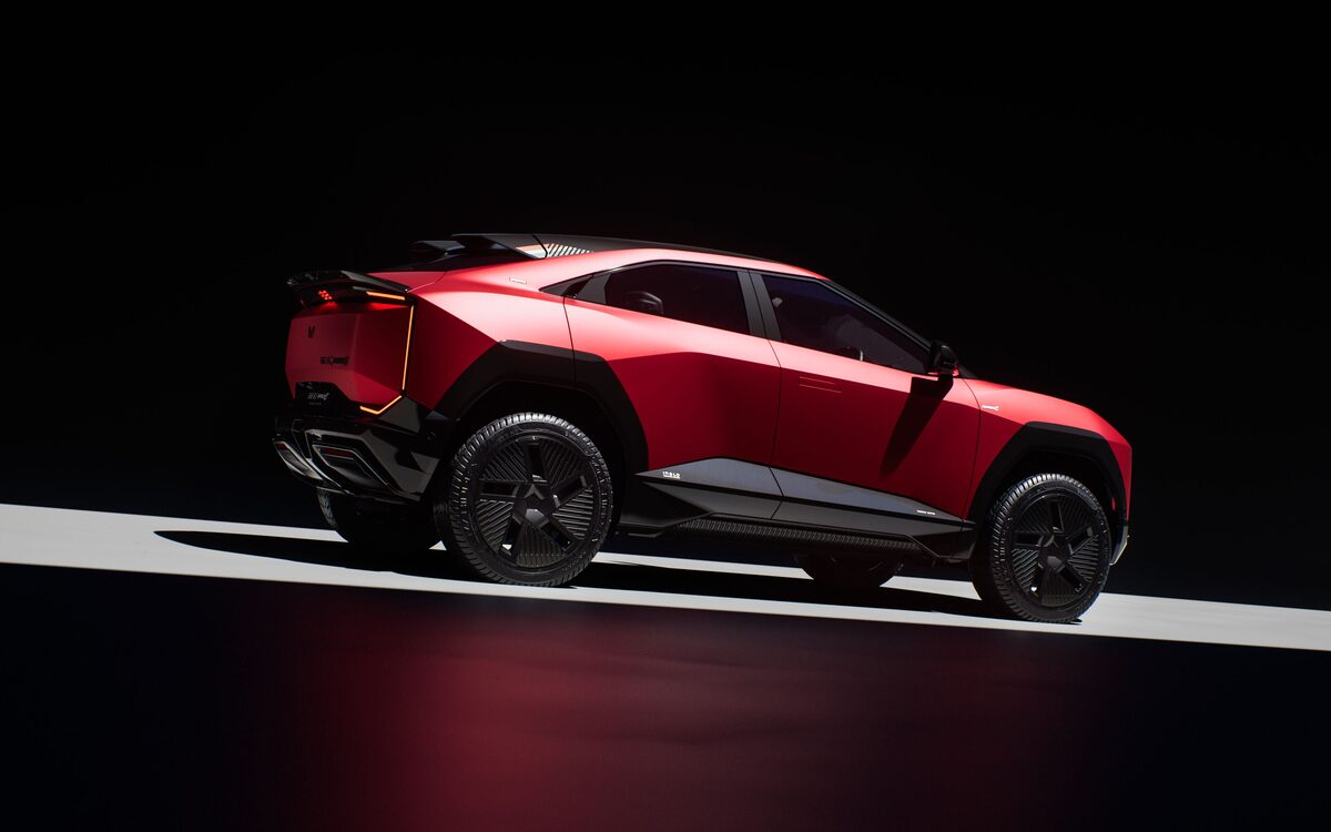 Mahindra BE 6 in red seen from the rear three-quarter angle with the glowing tail lamp and aero wheels