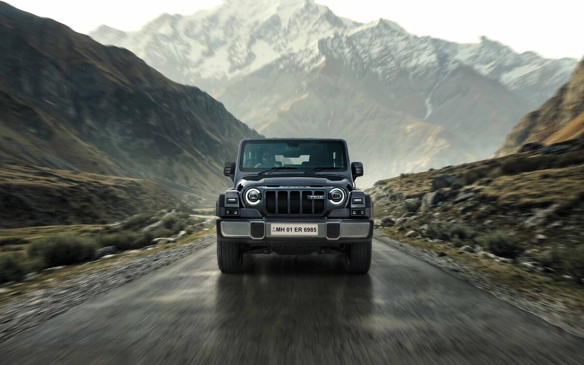 Mahindra Thar in grey driving straight at the camera on a wet mountain road