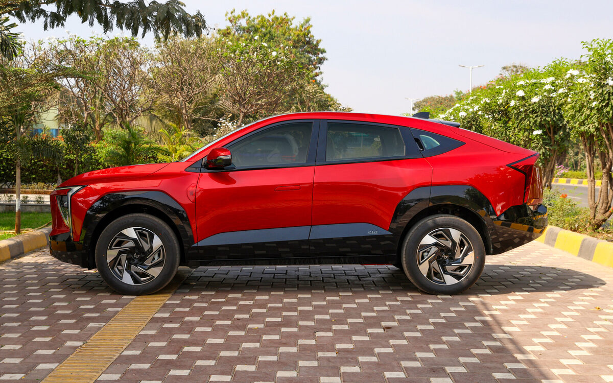 Mahindra XEV 9e in Tango Red, full side profile showing the coupe-style roofline