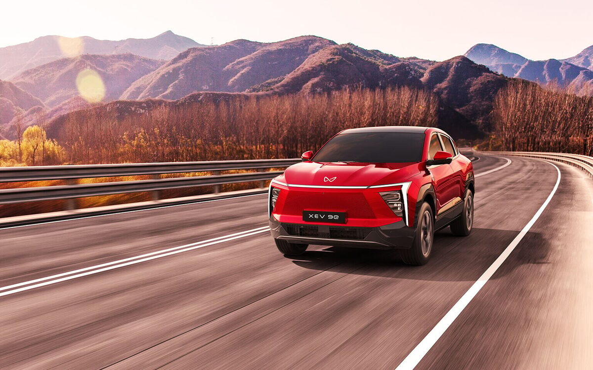 Mahindra XEV 9e in red driving on a mountain highway