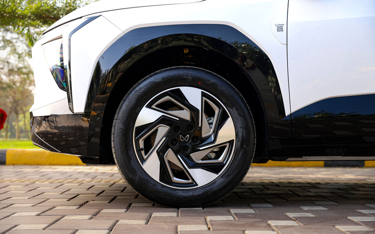 Close-up of the XEV 9e front alloy wheel on an Everest White car