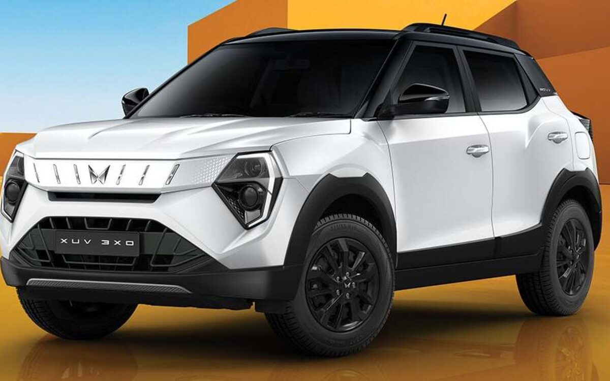 Mahindra XUV 3XO in white with a black roof, front three-quarter view against an orange backdrop