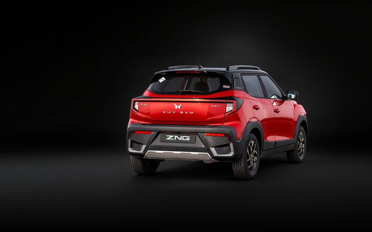 Red Mahindra XUV 3XO ZNG seen from the rear three-quarter on a dark studio background