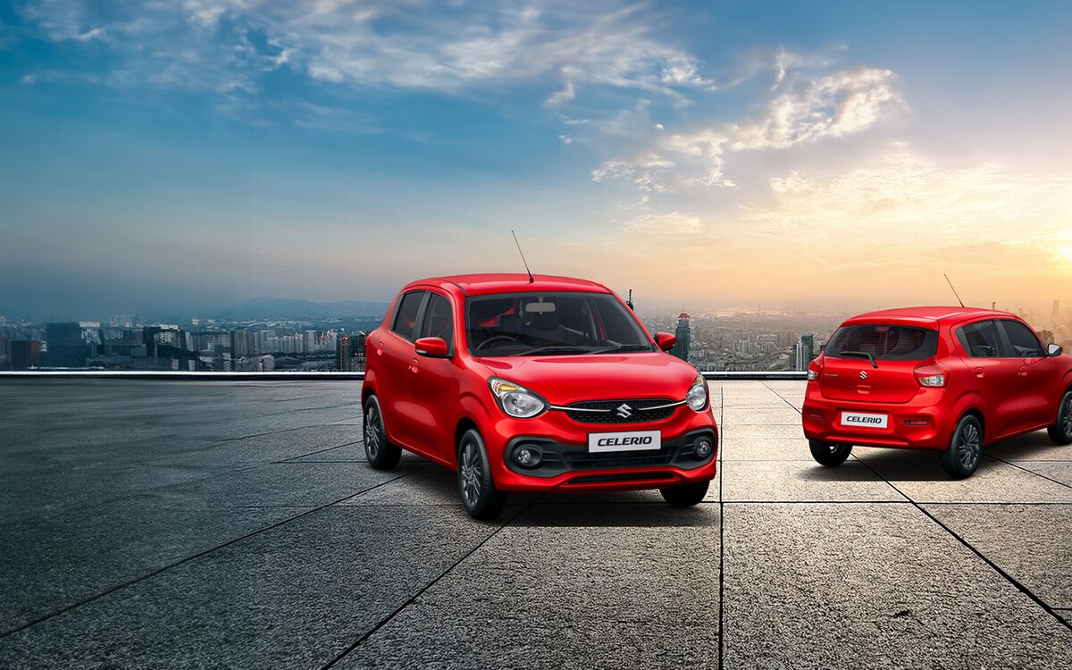 Two red Maruti Suzuki Celerio hatchbacks on a rooftop at sunset, one seen from the front and one from the rear