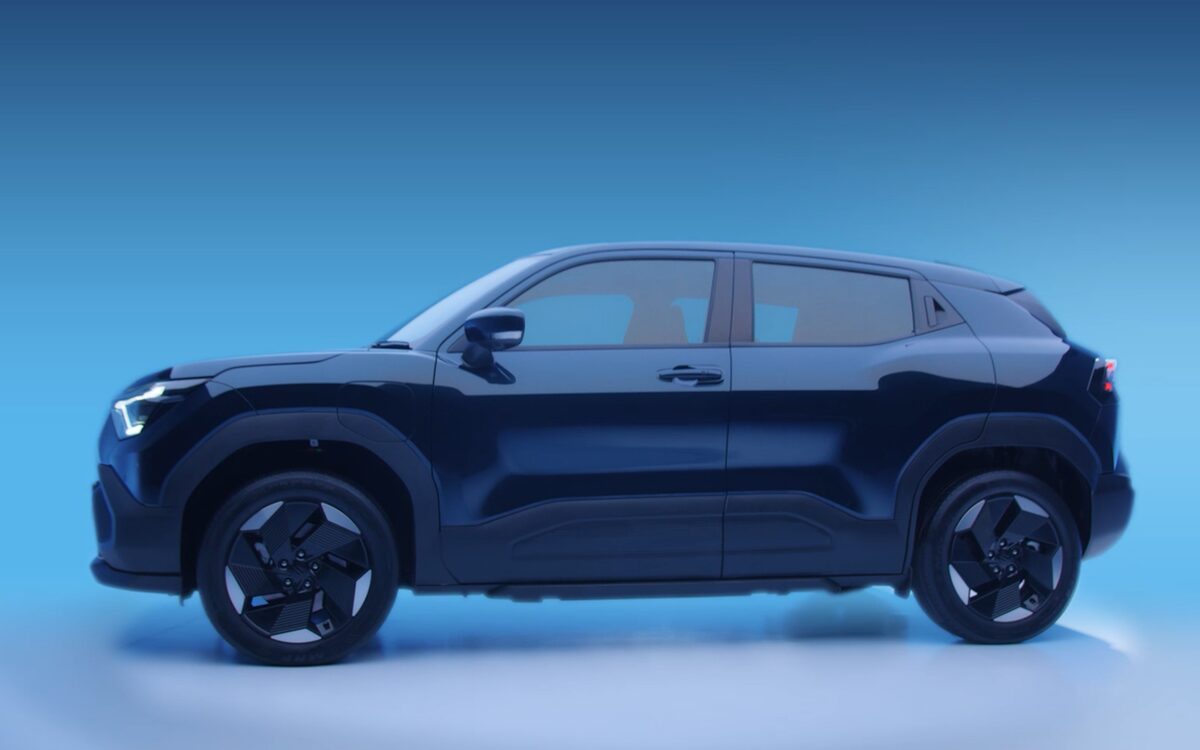 Maruti Suzuki e Vitara in dark blue, side profile against a blue studio backdrop