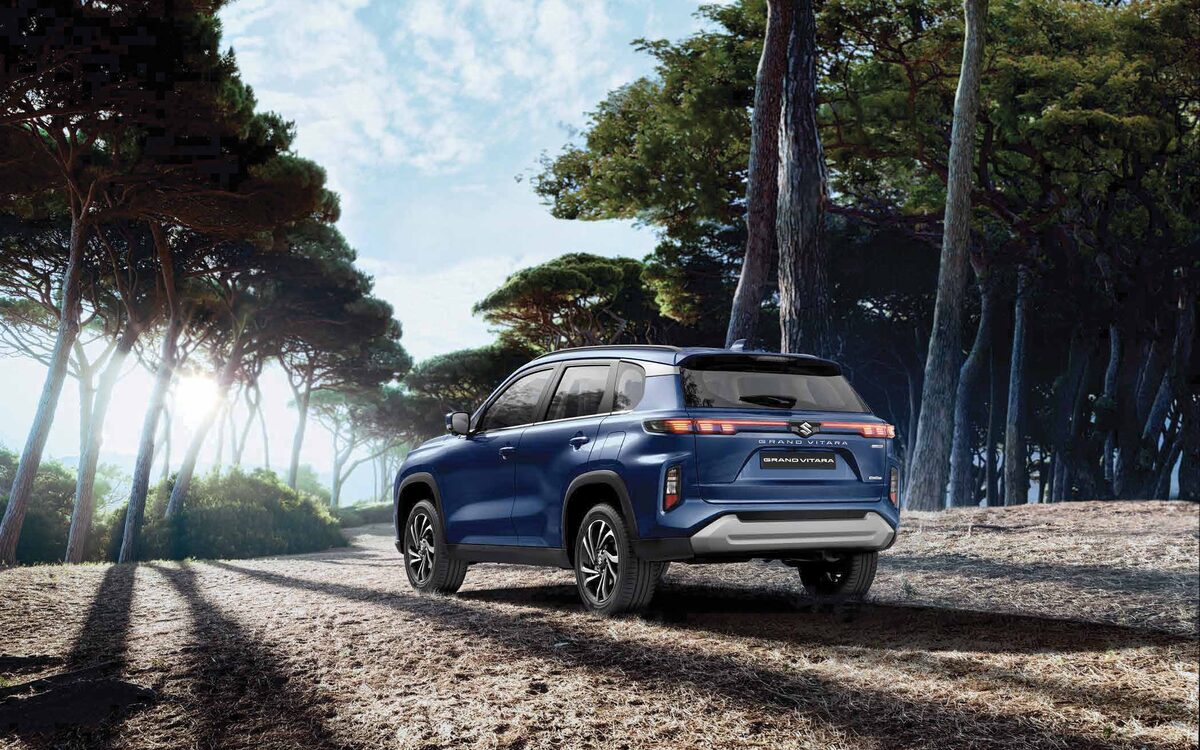 Maruti Suzuki Grand Vitara in Nexa Blue, rear three-quarter view on a forest road