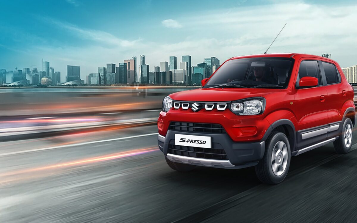 S-Presso in red driving on a highway with a city skyline behind