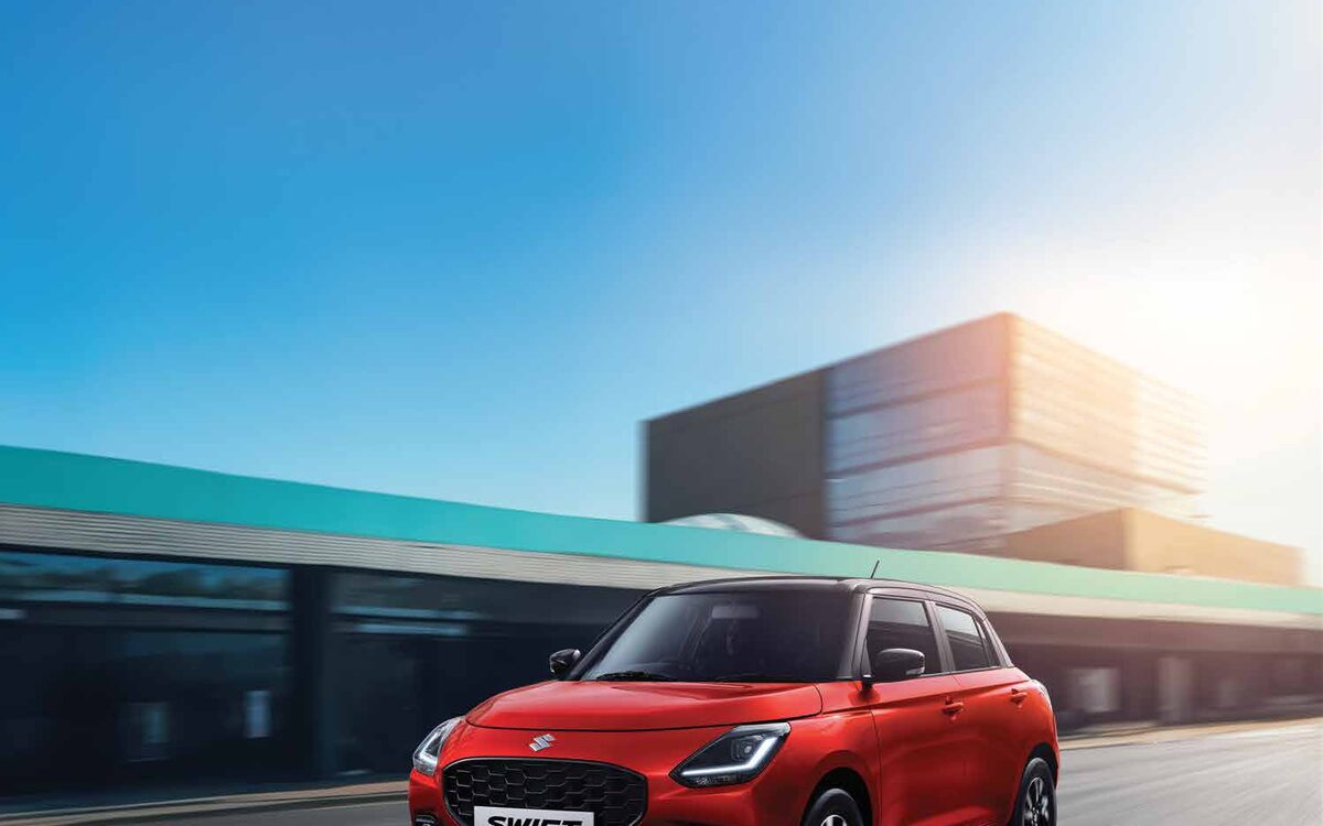 Maruti Suzuki Swift in red driving on a city road, front three-quarter view