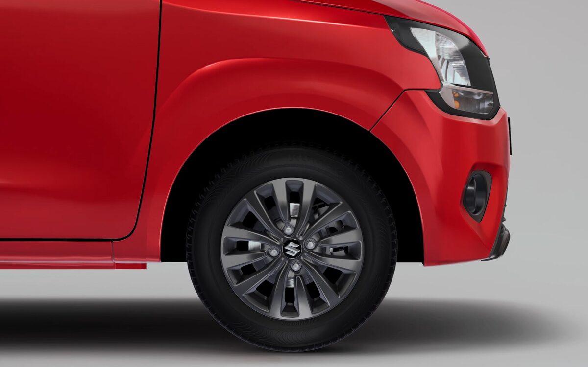 Close-up of the Wagon R's front wheel with dark alloy-style wheel cover and red front fender