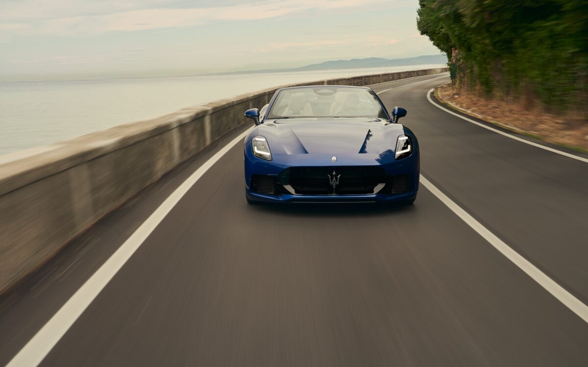 Blue Maserati GranCabrio driving towards the camera on a coastal road
