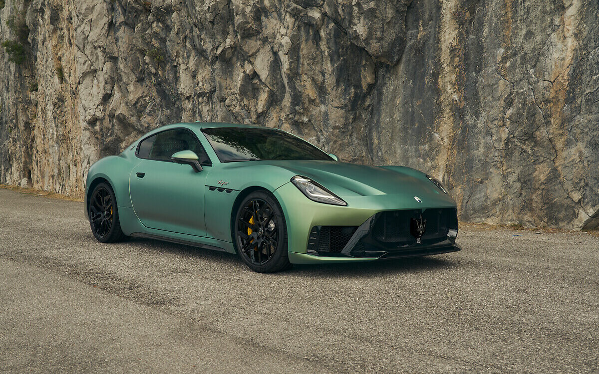 Maserati GranTurismo in a pale green paint, front three-quarter view beside a rock wall