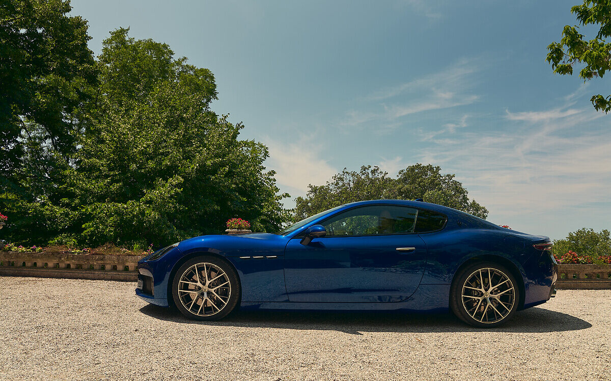 Maserati GranTurismo in blue, side profile on a gravel road