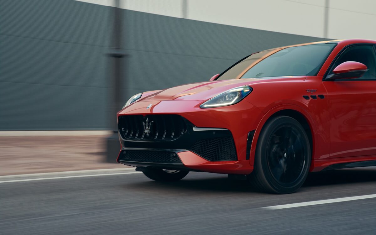 Red Maserati Grecale driving past a grey wall, front three-quarter view