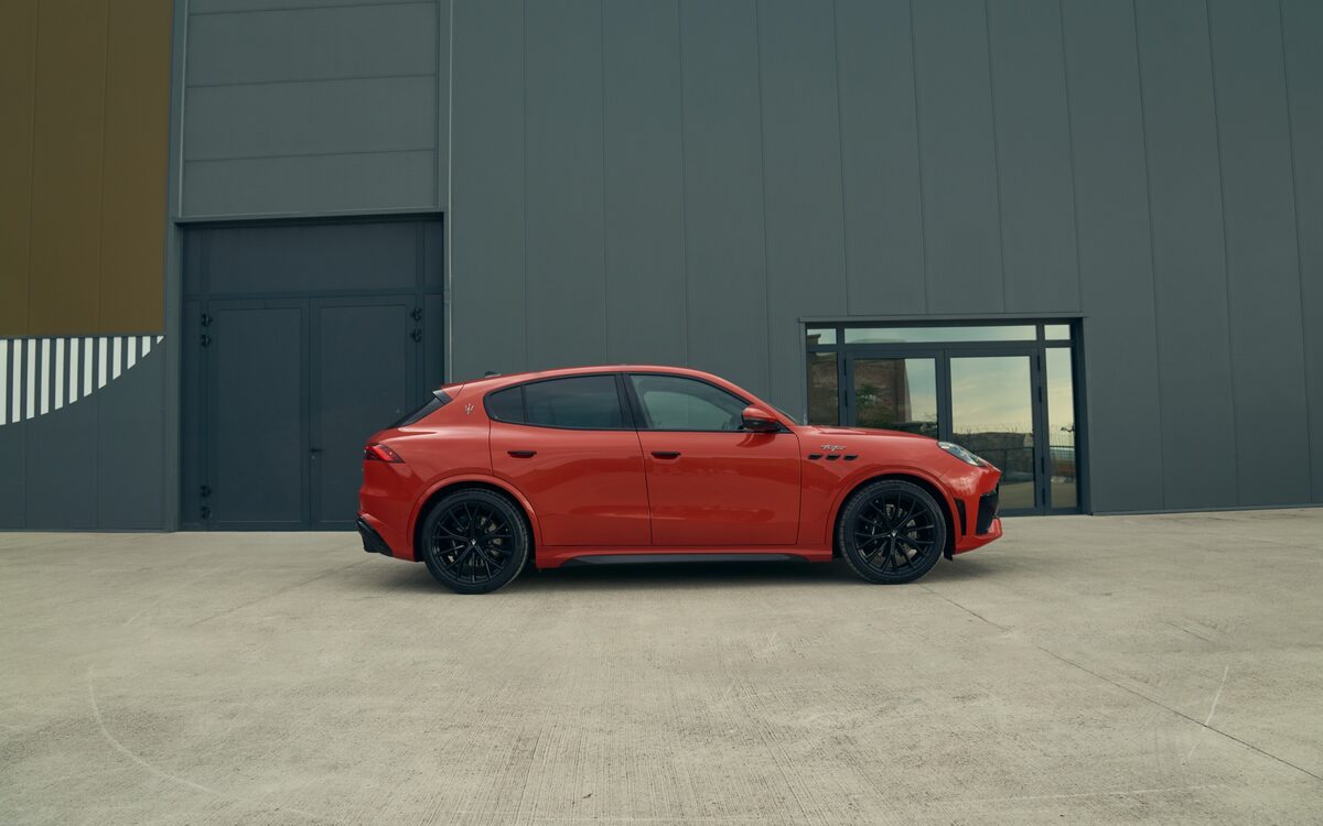 Red Maserati Grecale in side profile in front of a grey building