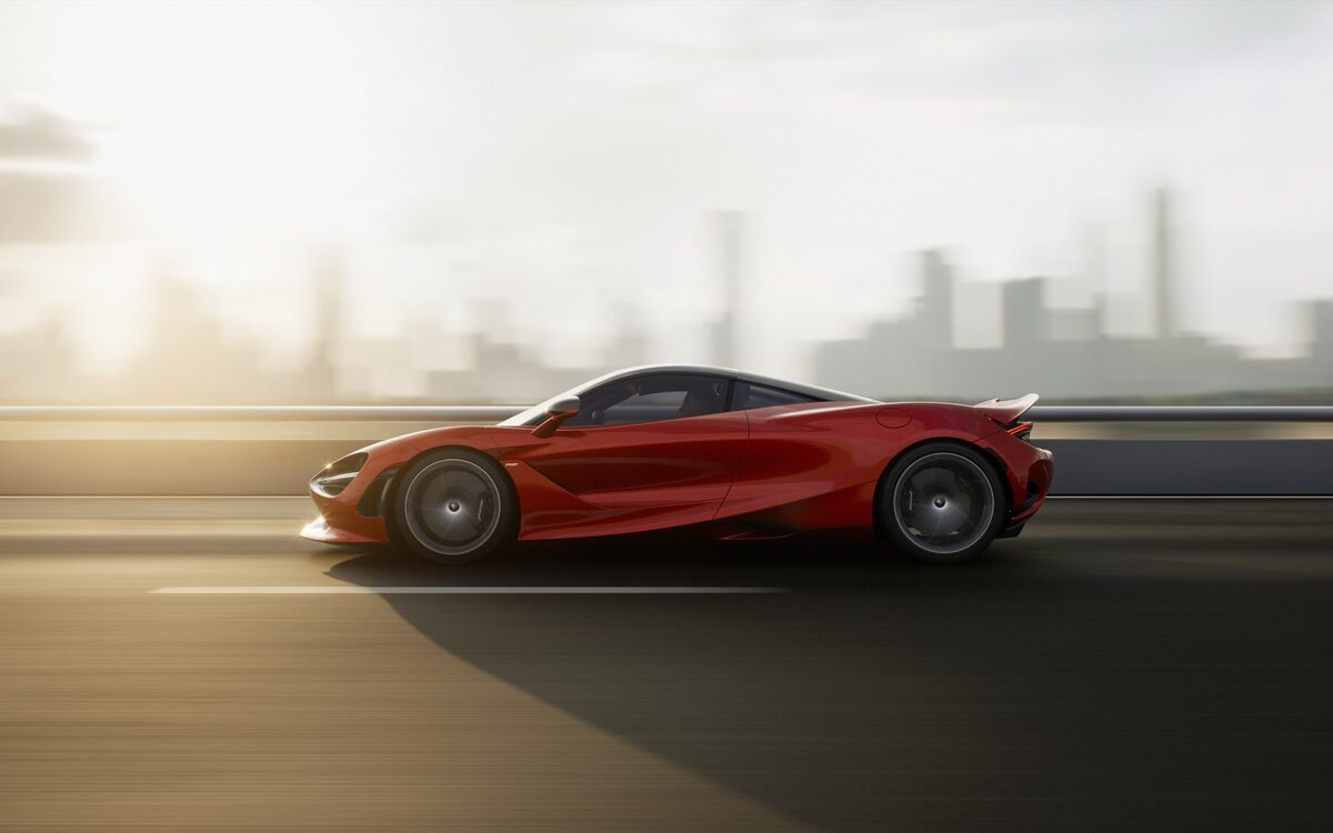 McLaren 750S in side profile driving on a road with a city skyline behind