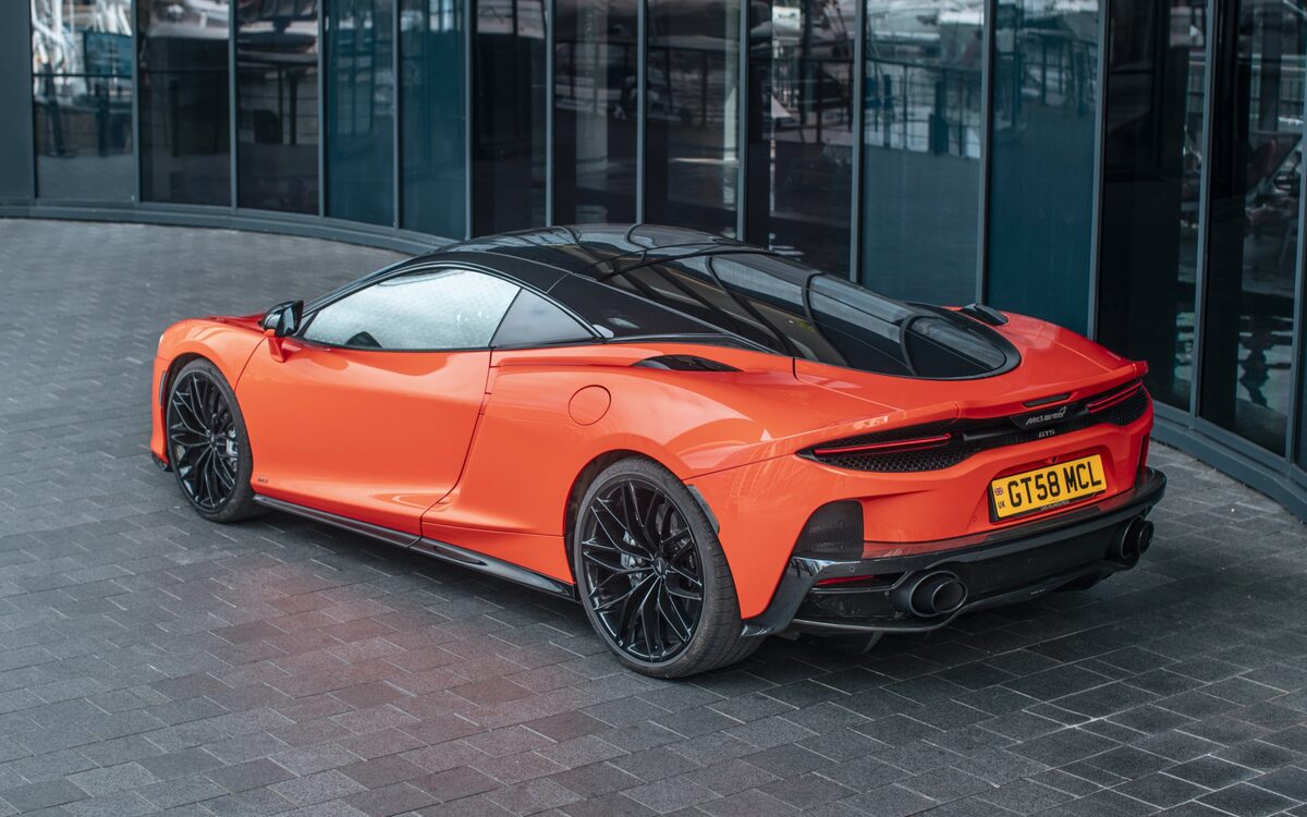 McLaren GTS in orange, rear three-quarter view parked on paved ground